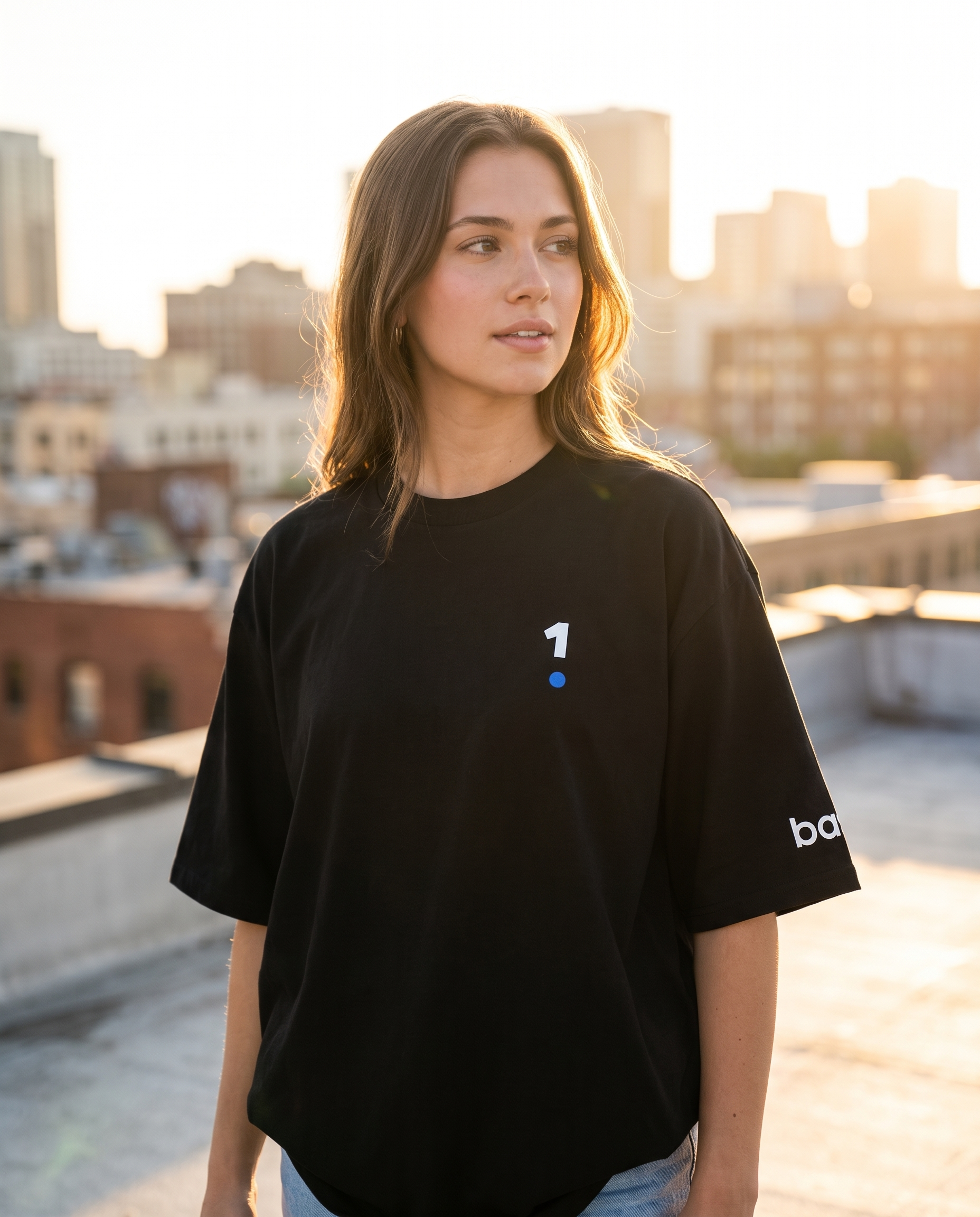 Woman wearing Base1 Logo Oversized Heavyweight Tee on a city rooftop