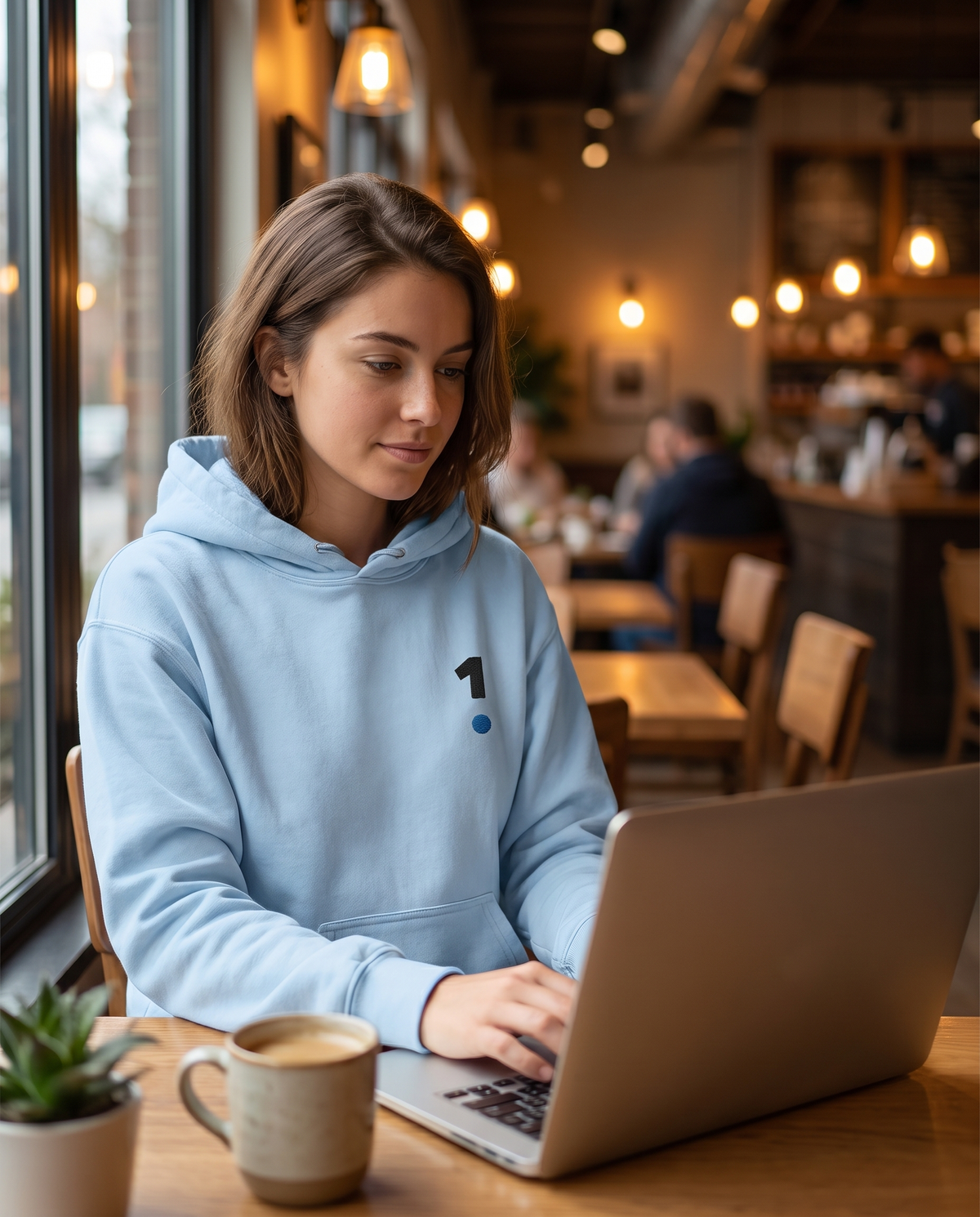 Woman wearing Base1 Logo Unisex Hoodie in a cafe
