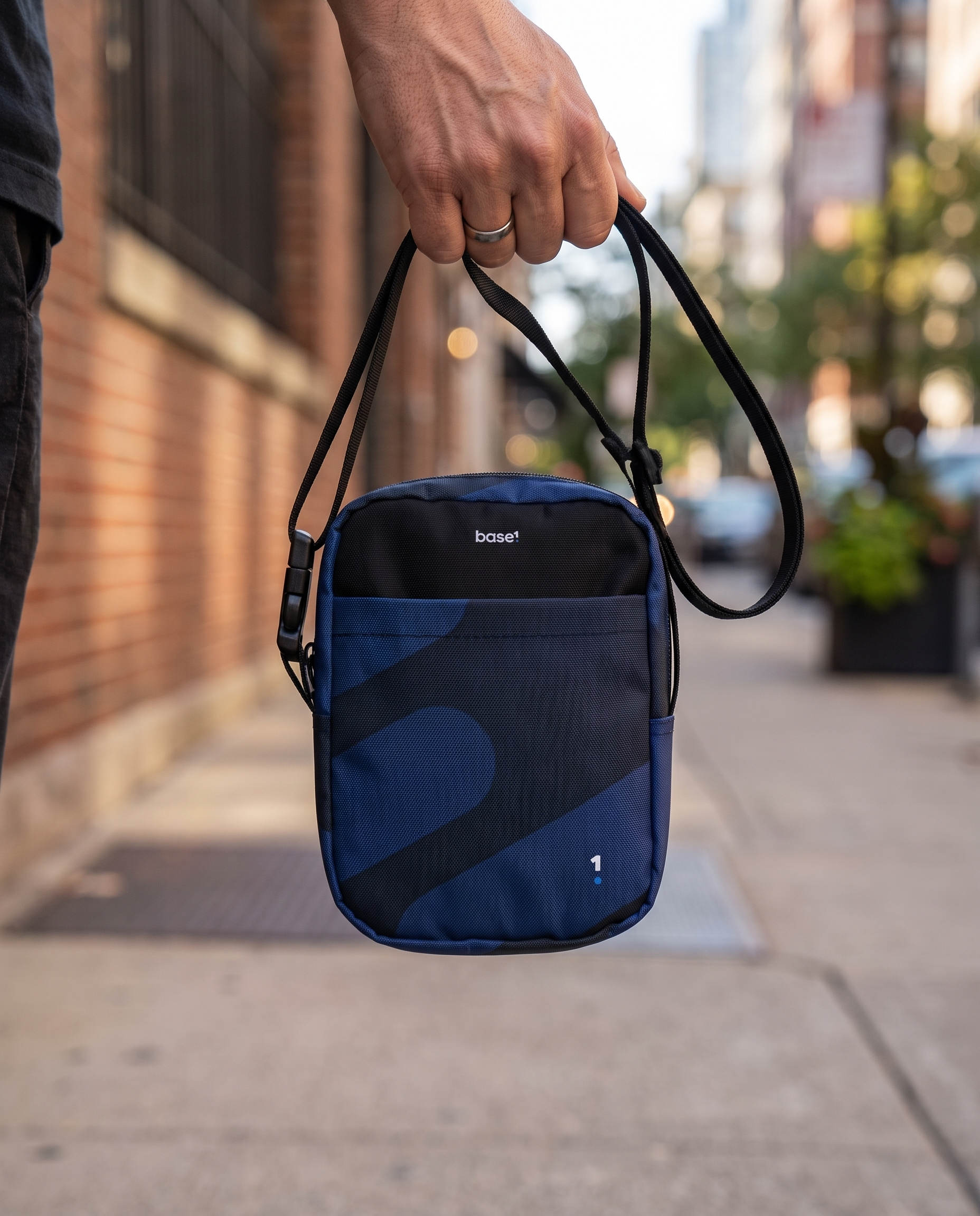 Base1 Utility crossbody bag held against an urban background