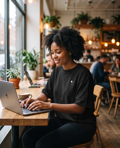 Woman wearing Base1 1 Logo Tee Essentials working in a cafe