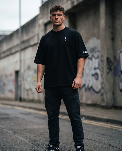 Man wearing Base1 Logo Oversized Heavyweight Tee on a city street