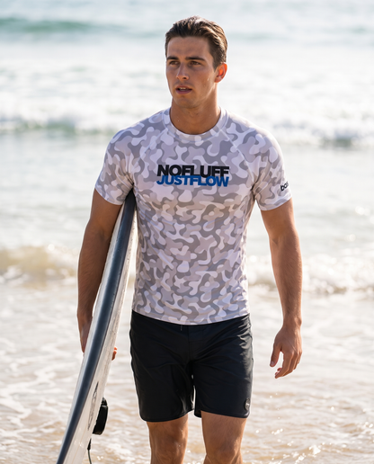 Man wearing Base1 No Fluff Just Flow rash vest on a beach